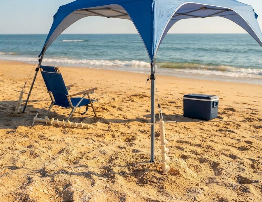 A UMARDOO canopy leg anchored in sand next to a chair and cooler